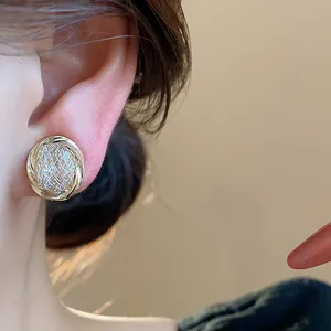 Close-up of a luxurious 18k gold plated zircon ear clip with a woven design