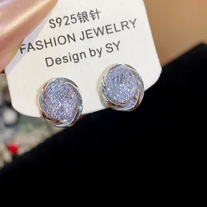 Close-up detail of geometric stud earrings featuring sparkling zircon and woven mesh design