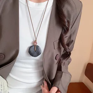 Collana con ciondolo in resina scura testurizzata vintage e un blazer marrone chic