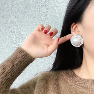 Gros plan de boucles d'oreilles perles avec halo de strass scintillants sur l'oreille