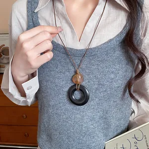 Lunga collana etnica retrò in resina con ciondolo circolare nero e perla ambrata