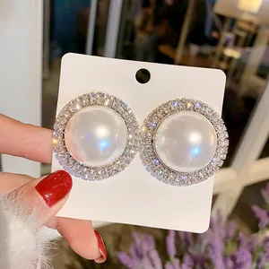 Vue détaillée de boucles d'oreilles perles surdimensionnées avec halo de strass