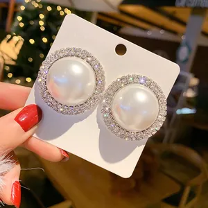 Vue détaillée des boucles d'oreilles perles géantes avec un halo de strass brillants
