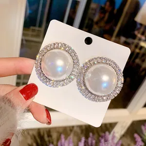 Détail en gros plan montrant de grandes boucles d'oreilles en perles avec halo de strass