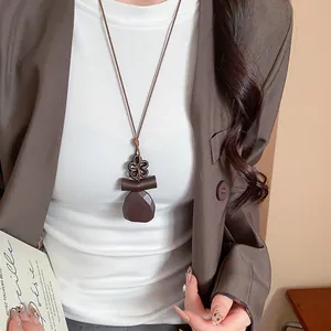 Dettaglio ravvicinato della collana vintage con ciondolo in resina su top