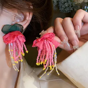 Detailed view of handmade pink floral tassel earrings with delicate beaded strands