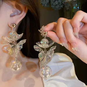 Detail of iridescent transparent flower earrings with large clear glass ball drops.