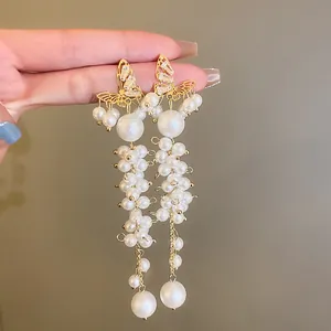 Detailed view of elegant gold butterfly earrings with long white pearl tassel dangles