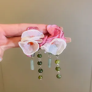 Elegant handmade pink fabric flower earrings with green bead tassels held in hand for detail