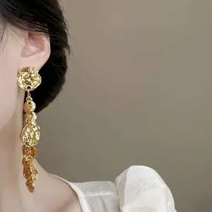 Primo piano di orecchini vintage in oro con nappe rotonde testurizzate su modella