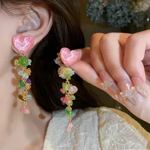 Close-up detail of vibrant multi-colored stone tassel earrings with pink heart stud