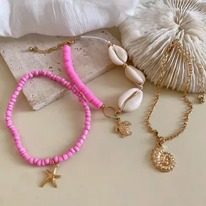 Detalle de set de joyas bohemias con cuentas rosas, conchas y dije de tortuga marina.