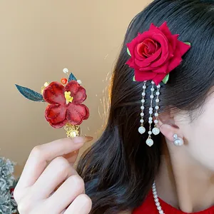 Elegante fermaglio per capelli a rosa in tessuto rosso con nappe di perle su modella.
