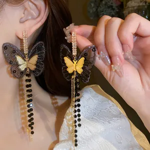 Close-up detail of exquisite black lace butterfly earrings featuring long gold chain tassels
