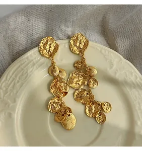Dettaglio degli orecchini vintage in metallo dorato martellato con nappe a disco