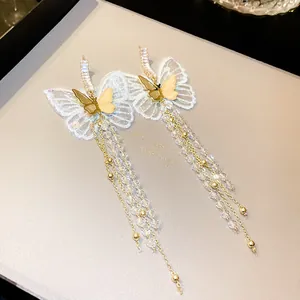 Close-up detail of elegant butterfly earrings with long beaded tassels and lace wings