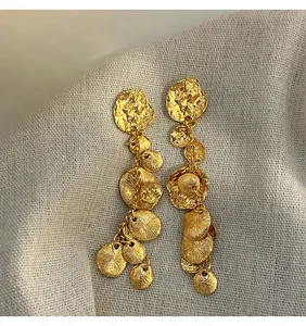 Primo piano di orecchini vintage a nappa dorata con dischi di metallo martellato
