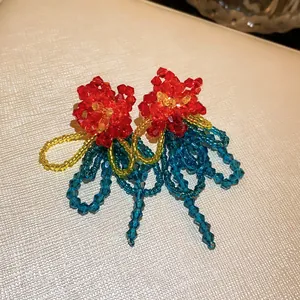 Detailed view of handmade beaded flower earrings with vibrant red, blue, and yellow tassels