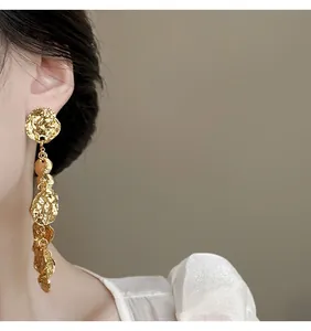 Dettaglio di eleganti orecchini in metallo dorato con pendenti rotondi testurizzati