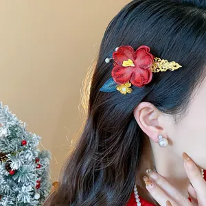 Dettaglio del fermaglio per capelli a fiore rosso con foglie dorate sui capelli della modella