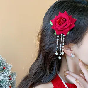 Dettaglio ravvicinato di un fermaglio per capelli a rosa rossa con nappe di perle