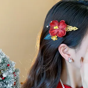 Vista dettagliata di un fermaglio per capelli a fiore rosso con filigrana dorata