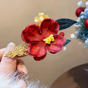 Primo piano di un elegante fermaglio per capelli con fiore rosso, filigrana dorata e perle
