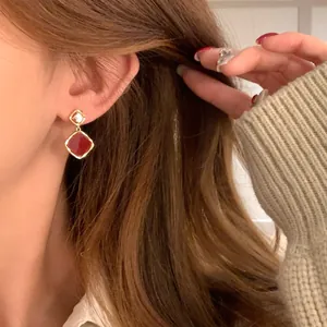 Close-up of elegant 18k gold plated earrings featuring vintage red square gemstones