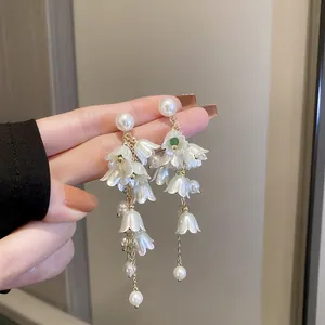 Elegant lily of the valley tassel earrings with white pearls and green bead detail.