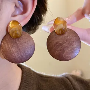 Close-up of vintage Maillard style round wooden earrings with amber resin detail