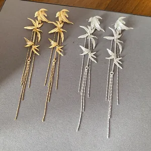 Close-up detail of new Chinese style bamboo leaf tassel earrings in gold and silver
