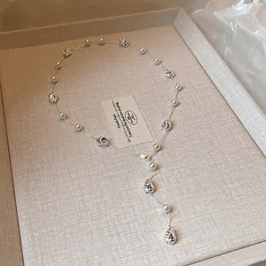 Dettaglio della collana minimalista con perline d'argento stropicciate e perle.