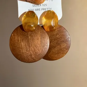 Macro view of vintage style round wooden earrings with amber resin top detail on display card
