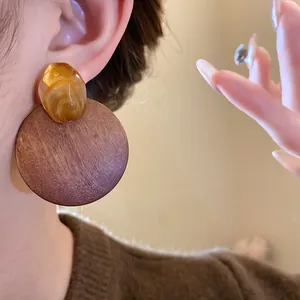 Detailed view of vintage circular wooden earrings with amber resin accents worn on ear