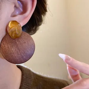 Detail shot showing a vintage Maillard style round wooden earring with amber resin stud
