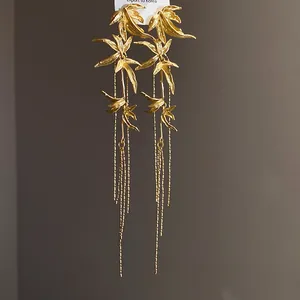 Detailed view of gold bamboo leaf tassel earrings with delicate metal chains