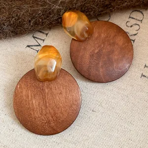 Macro detail of retro wooden round earrings featuring amber-colored resin studs.