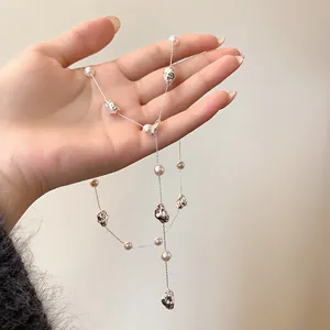Dettaglio di una collana di perle finte con perle geometriche plissettate argento