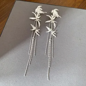 Detailed view of elegant silver-toned bamboo leaf earrings with long flowing tassels