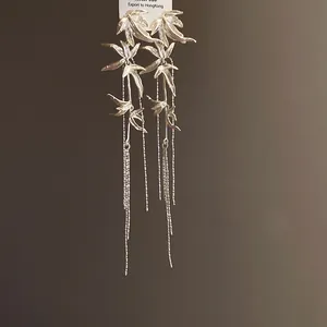 Detailed macro view of silver bamboo leaf tassel earrings with delicate hanging chains