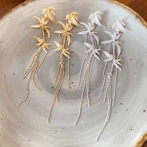Close-up detail of new Chinese style bamboo leaf tassel earrings in gold and silver matte finishes