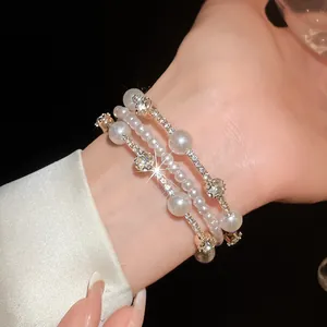 Vista detallada de una lujosa pulsera multicapa de perlas y pedrería en la muñeca