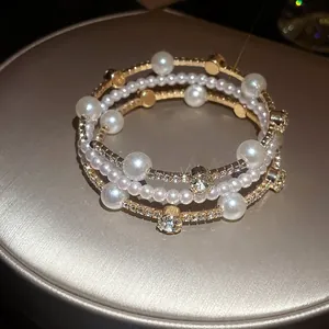 Primer plano del brazalete de perlas y diamantes de imitación con acabado dorado