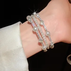 Primer plano detallado de una elegante pulsera multicapa de perlas y pedrería en la muñeca