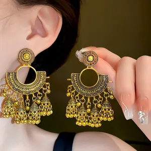 Close-up of vintage gold fan-shaped earrings with delicate bell tassels and ethnic design.