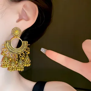 Detailed view of vintage golden fan-shaped tassel earrings worn by a model on ear