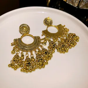 Detailed macro view of vintage gold fan-shaped earrings featuring delicate bell tassels
