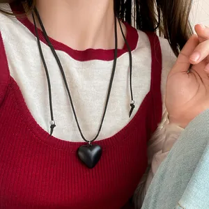 Close-up of a black resin heart pendant on an adjustable cord worn by a model