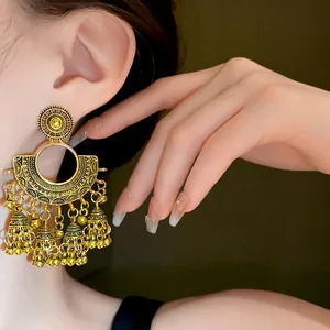 Close-up detail of vintage fan-shaped earrings with bell tassels in antique gold finish