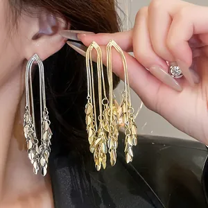 Dettaglio di eleganti orecchini lunghi a nappa geometrica in oro e argento